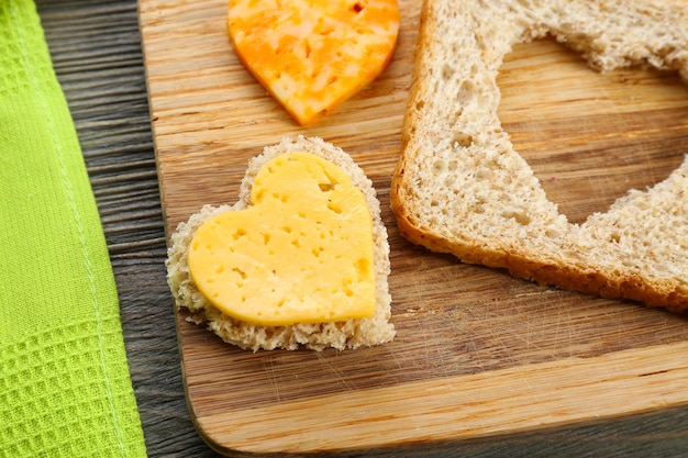 Rebanada de pan con corte en forma de corazón y queso en la mesa de cerca