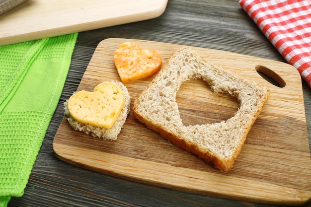 Rebanada de pan con corte en forma de corazón y queso en la mesa de cerca