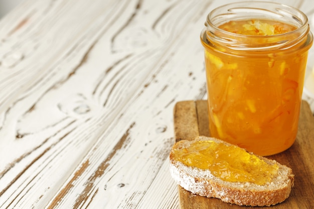 Rebanada de pan cubierto con mermelada de frutas sobre tabla de madera