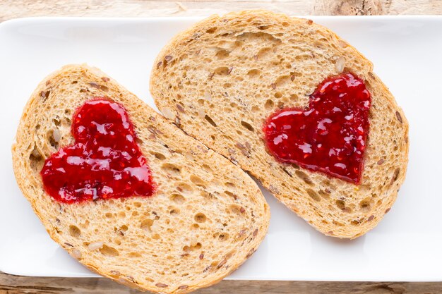Rebanada de pan de grano con forma de corazón de mermelada.