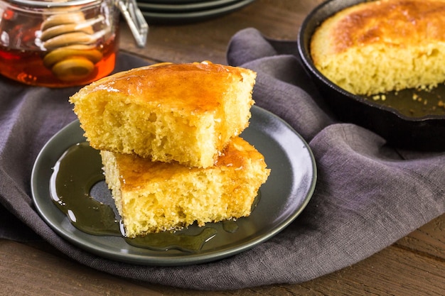 Rebanada de pan de maíz dulce con miel en el plato.