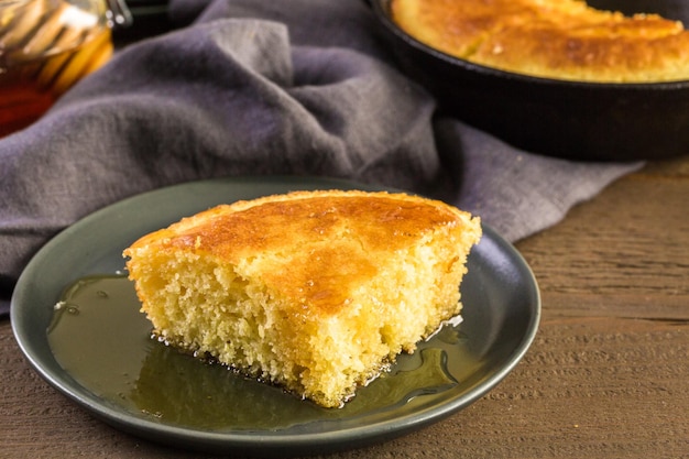 Rebanada de pan de maíz dulce con miel en el plato.