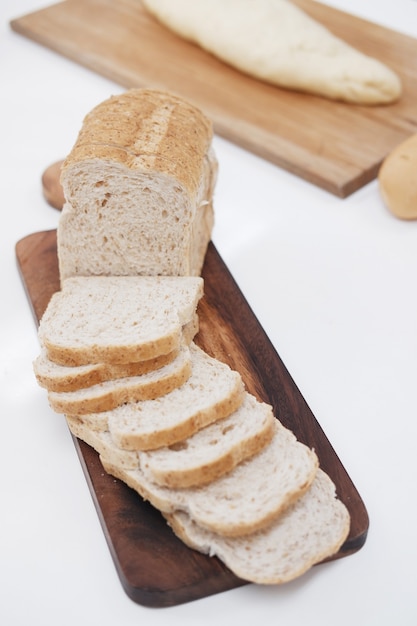 Rebanada de pan de trigo integral está cortando en madera. Pastelería casera para menú de desayuno sabroso y saludable.