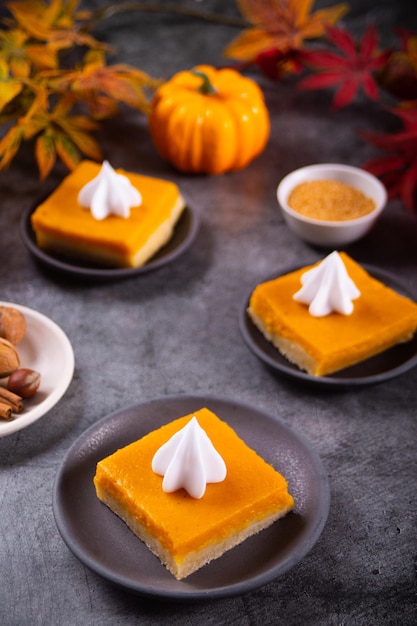 Rebanada de pastel de calabaza casero americano tradicional recién horneado cortado en trozos cuadrados decorando crema batida para celebrar las fiestas