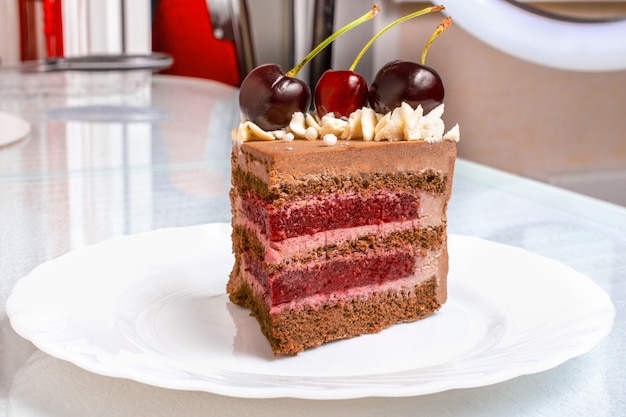 Rebanada de pastel de caramelo de chocolate con cerezas en plato blanco