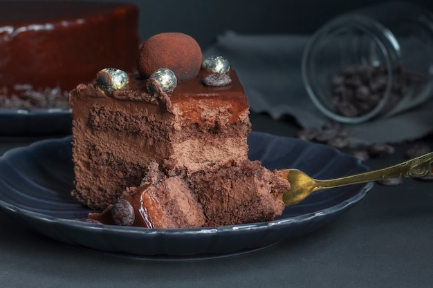 Una rebanada de pastel de chocolate brownie, postre con nueces en la oscuridad