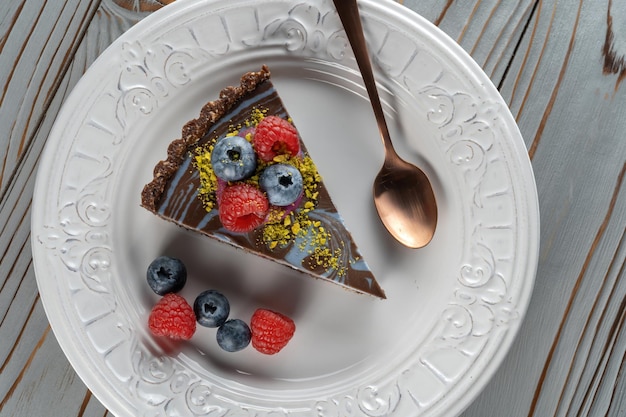 Rebanada de pastel de chocolate con nueces decorado con bayas, arándanos y frambuesas