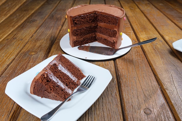 Rebanada de pastel de chocolate con relleno y glaseado de ganache de chocolate semidulce Junto al pastel en rodajas