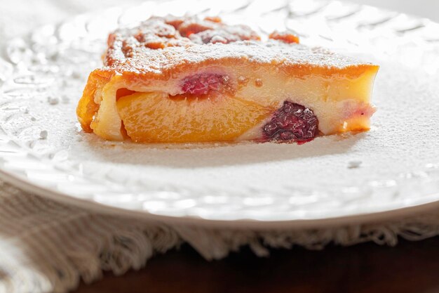 Foto una rebanada de pastel de clafoutis con melocotones frambuesas y moras