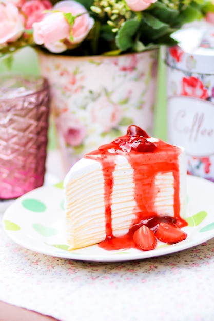 Foto una rebanada de pastel de crepé con salsa de fresa jugosa en la parte superior