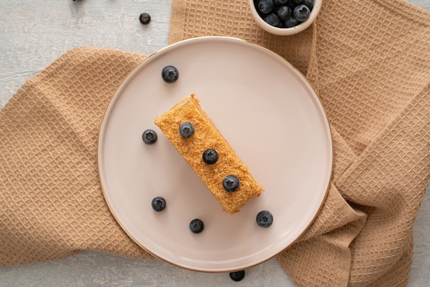 Rebanada de un pastel cubierto con arándanos frescos en la placa blanca.