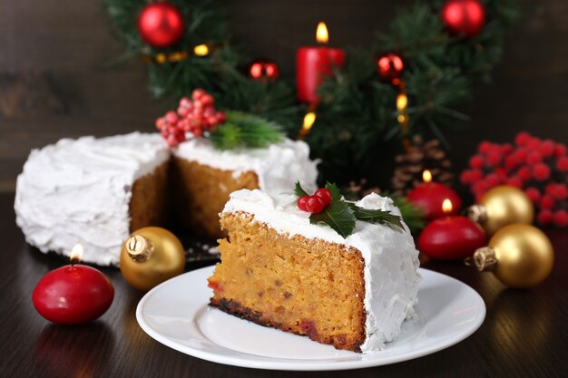 Rebanada de pastel cubierto de crema con decoración de Navidad sobre fondo de mesa de madera