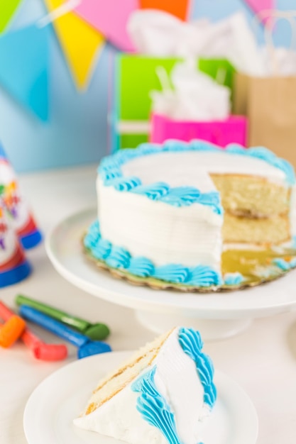 Rebanada de pastel de cumpleaños blanco simple con glaseado blanco y azul.
