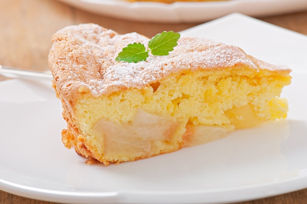 Rebanada de pastel de manzana en un plato decorado con hojas de menta