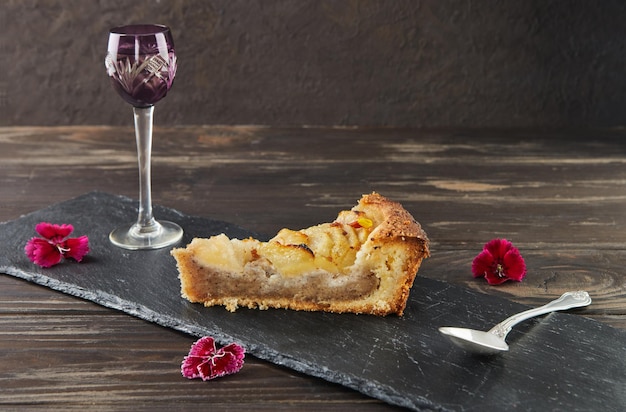 Rebanada de pastel de pera y durazno con crema de avellanas, avellanas y flores comestibles. Cocina gourmet francesa.