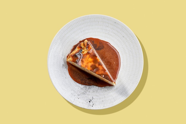 Una rebanada de pastel de queso cremoso con una corteza caramelizada salpicada con una rica salsa de caramelo