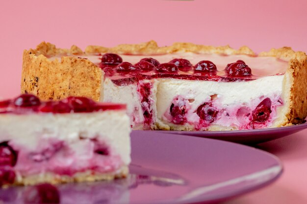 Foto rebanada de pastel de queso con salsa de arándanos en un plato blanco decorado con hojas de menta. vista de cerca