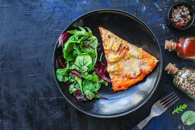 rebanada de pizza y ensalada de hojas en un plato