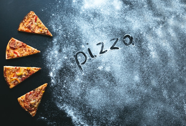 Rebanada de pizza sobre fondo negro, con espacio para texto y harina. Texto pizza Italia