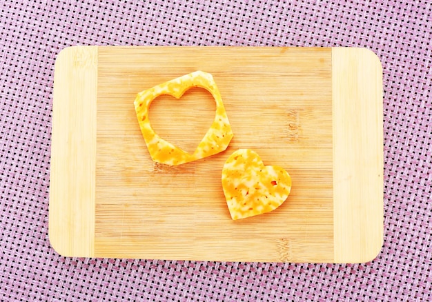 Rebanada de queso con corte en forma de corazón sobre fondo de madera