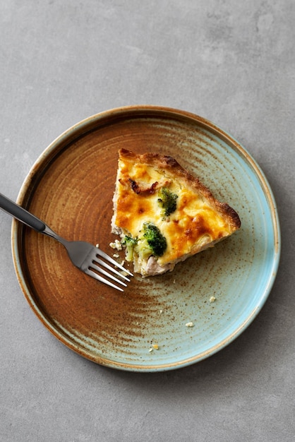 Rebanada de quiche casera con brócoli de pollo y queso sobre un fondo de hormigón Vista superior