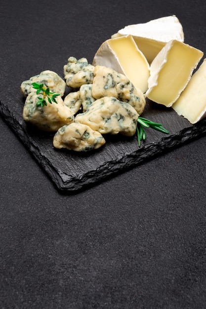 Rebanada de Roquefort francés y queso brie sobre tabla de piedra