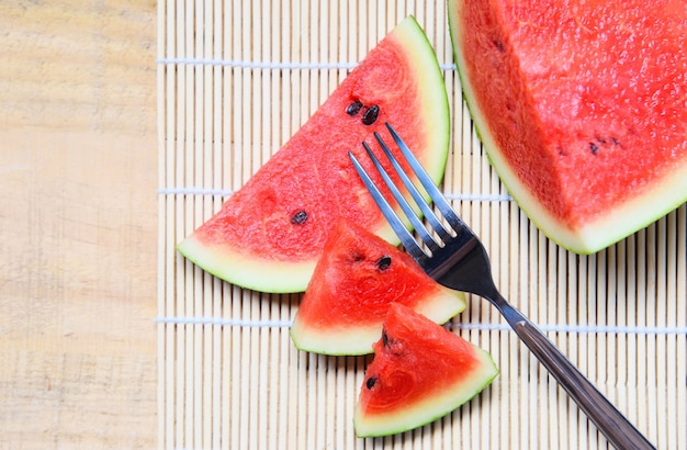 Rebanada de sandía en placa de madera con una fruta tenedor