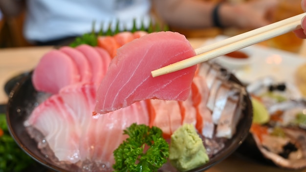 Rebanada de sashimi de atún en los palillos.