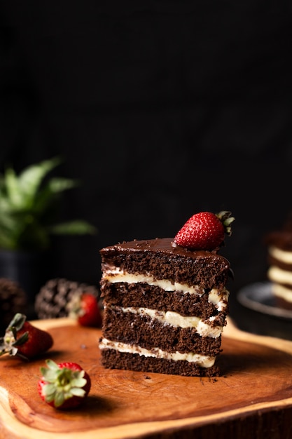 Rebanada de tarta de chocolate casera con deliciosa fresa sobre la mesa