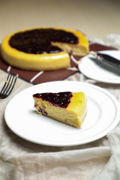 La rebanada de tarta de queso con arándanos incluye caramelo con tenedor y cuchillo servido en un plato aislado en la vista superior de la mesa de la comida horneada en el café