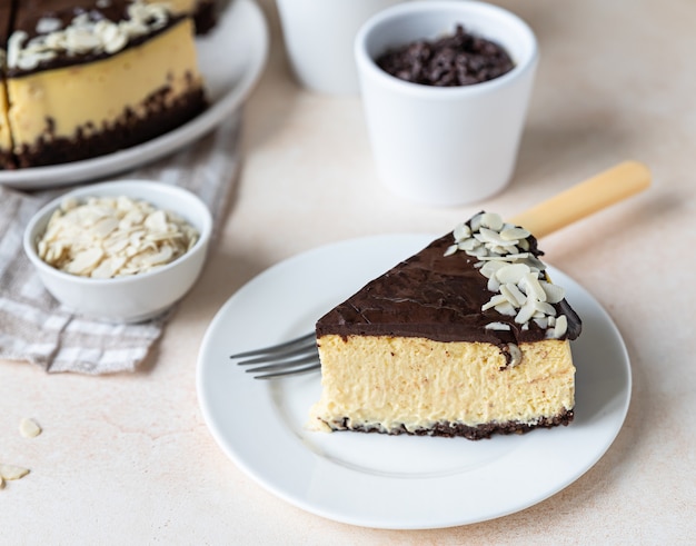 Rebanada de tarta de queso cremosa con glaseado de chocolate y almendras