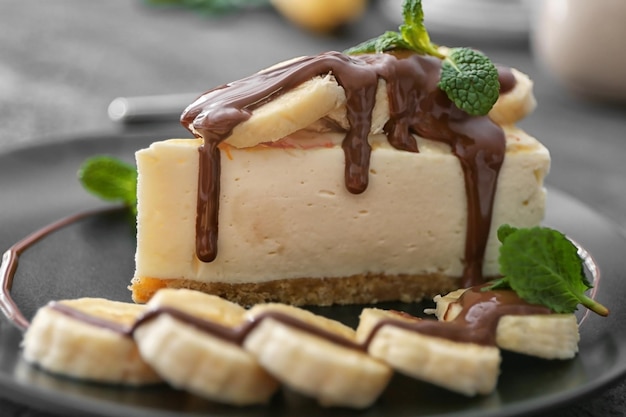 Rebanada de tarta de queso sabroso con chocolate y plátanos en la placa