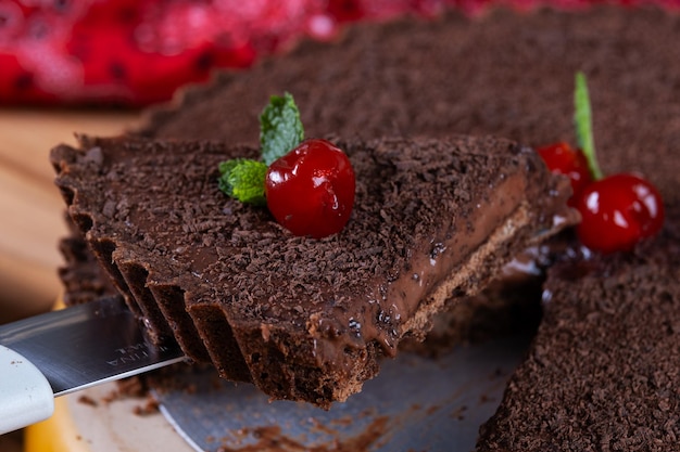 una rebanada tomada de un pastel de chocolate oscuro decorado con cerezas