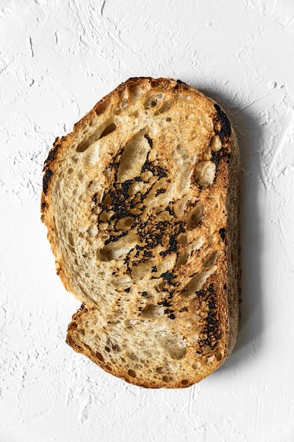 Una rebanada tostada de pan de trigo integral en la vista superior de fondo blanco