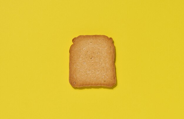 Una rebanada de tostada de trigo blanco en un fondo amarillo vista superior