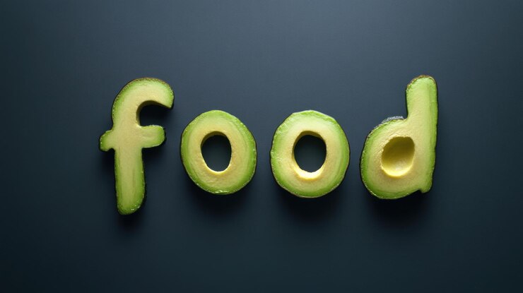 Foto rebanadas de aguacate dispuestas para deletrear la palabra "foodquot" sobre un fondo gris oscuro