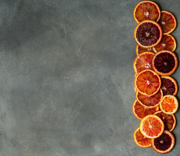 Rebanadas anaranjadas sicilianas jugosas de la sangre en fondo gris. Textura de naranja de sangre en rodajas. Fondo de cítricos.