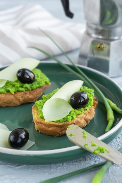 Rebanadas de Baguette de pan de ajo con mantequilla de ajo, queso de aceitunas y flechas de ajo en placa verde