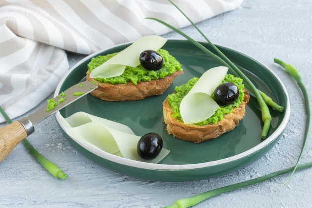 Rebanadas de Baguette de pan de ajo con mantequilla de ajo, queso de aceitunas y flechas de ajo en placa verde