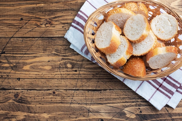 Rebanadas de baguette de pan blanco fresco en una cesta de mimbre Fondo de mesa rústico de madera Espacio de copia