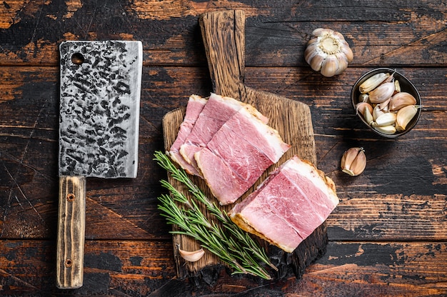 Foto rebanadas de carne de cerdo ahumado jamón sobre una tabla de cortar rústica de madera.