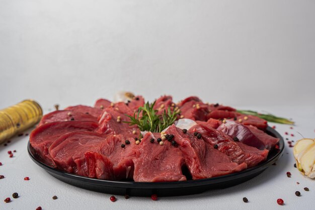 Rebanadas de carne cruda con romero y especias de bistec sobre fondo blanco