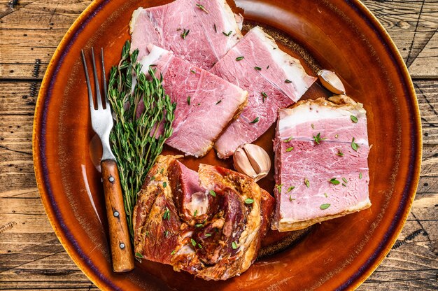 Foto rebanadas de carne de tocino de losa de cerdo ahumado en un plato rústico.