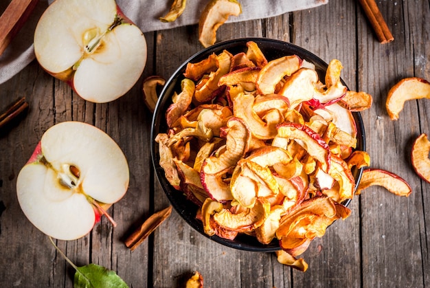 Rebanadas caseras de manzana orgánica seca, chips de manzana crujientes, sobre una vieja mesa de madera rústica con manzana fresca y canela. vista superior de copyspace