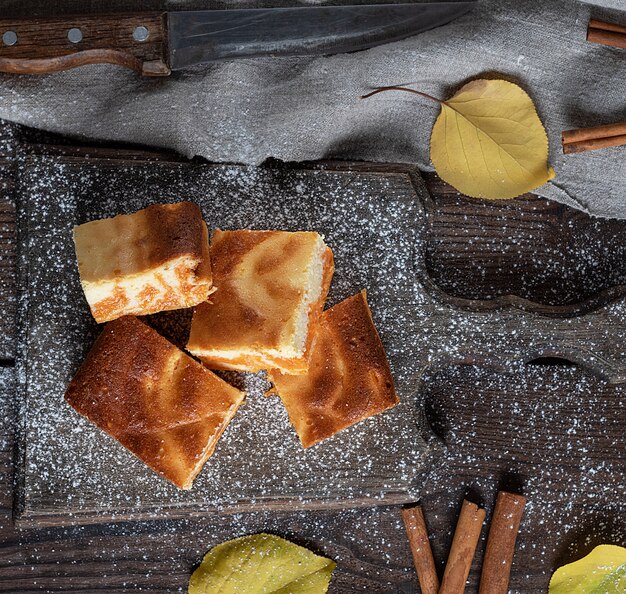 Rebanadas cuadradas de requesón y pastel de calabaza en el tablero de madera