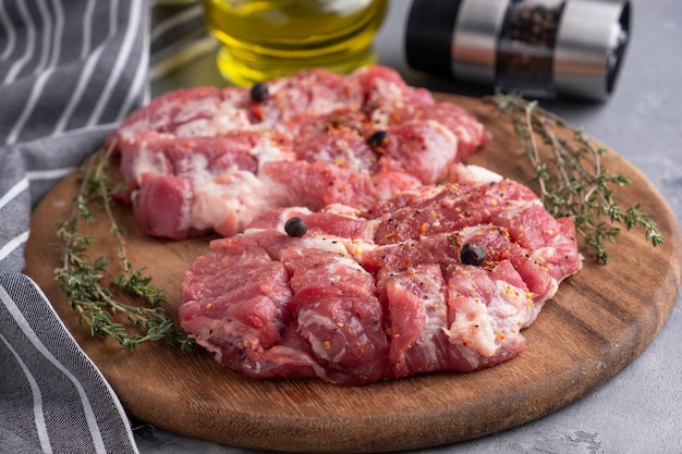 Rebanadas de cuello de cerdo crudo sobre tabla de madera. De cerca