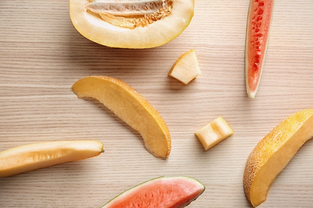 Rebanadas de delicioso melón fresco y sandía en la vista superior de la mesa de madera