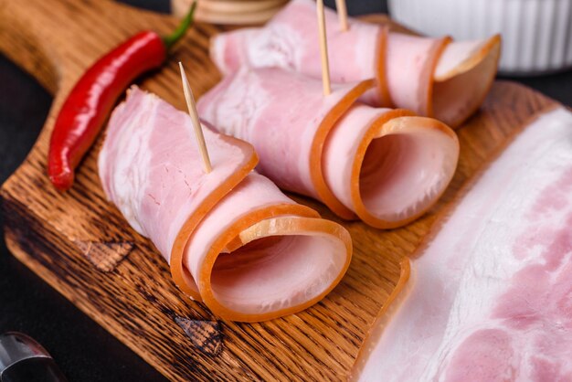 Rebanadas de delicioso tocino crudo o salado con especias, sal, verduras y hierbas en una tabla de cortar de madera