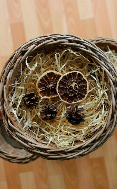Rebanadas deshidratadas de pomelo y piñas en un nido de virutas en una olla de mimbre casera