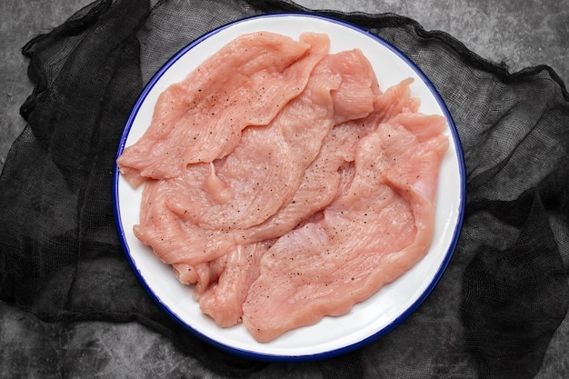 Rebanadas de filete de carne de pavo crudo en plato blanco